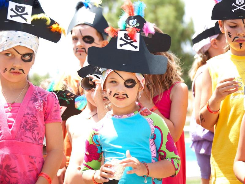 Bambini vestiti da pirati con cappelli e trucco durante un evento all'aperto soleggiato.