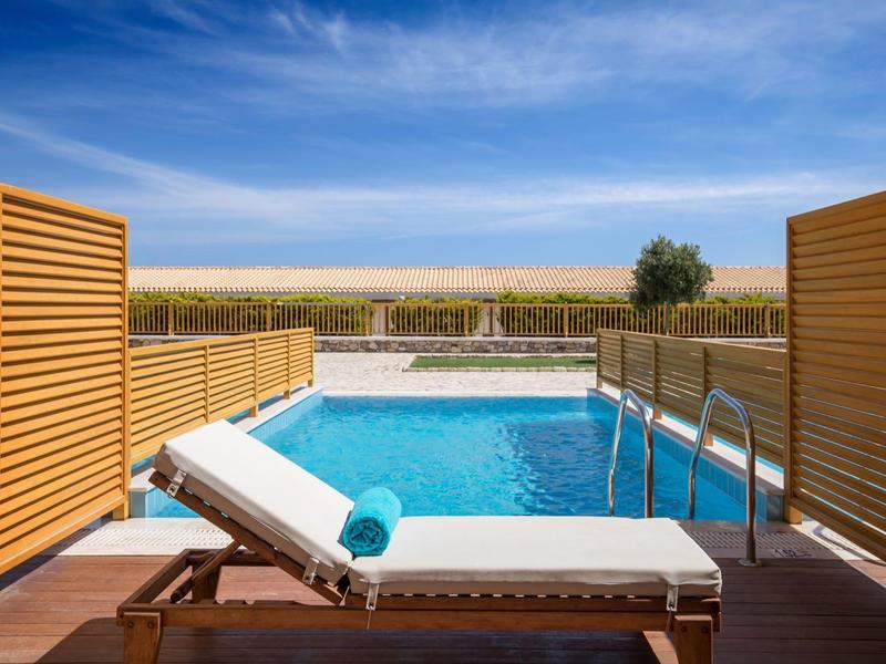 Area piscina privata con lettino e asciugamano blu, vista su paesaggio aperto sotto cielo azzurro.