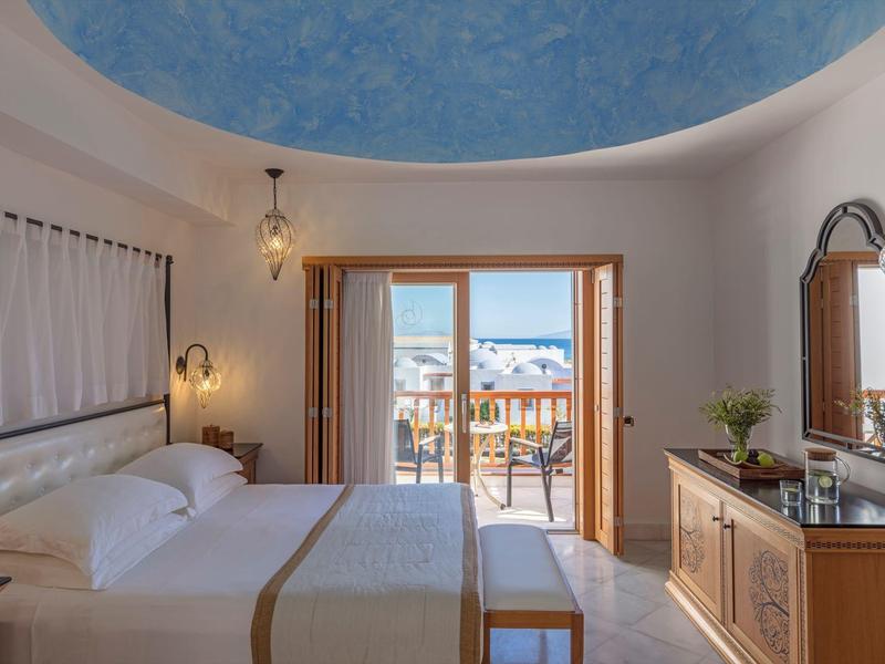 Camera d'hotel accogliente con letto matrimoniale, balcone e vista sulle montagne.