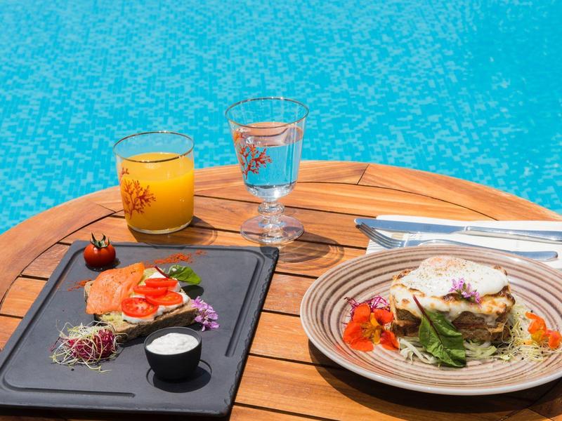Colazione con succo e acqua su un tavolo di legno vicino a una piscina