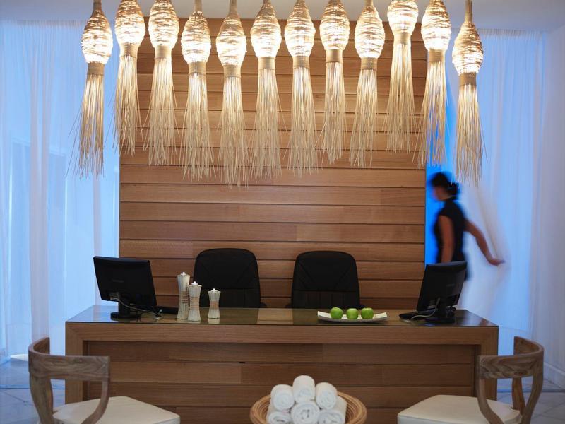 Banco reception con sedie, asciugamani arrotolati e lampade a lanterna sospese in toni caldi.