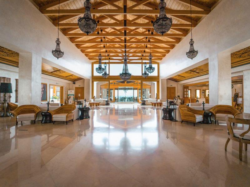 Ampia hall dell'hotel con soffitto in legno, pavimenti lucidati e aree salotto eleganti.