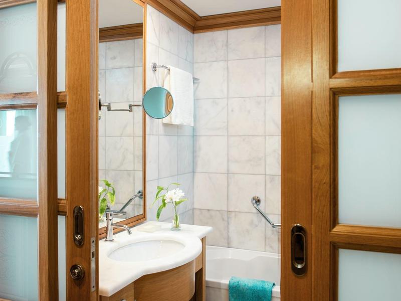 Bagno con vasca bianca, lavabo e specchio in una camera d'hotel.