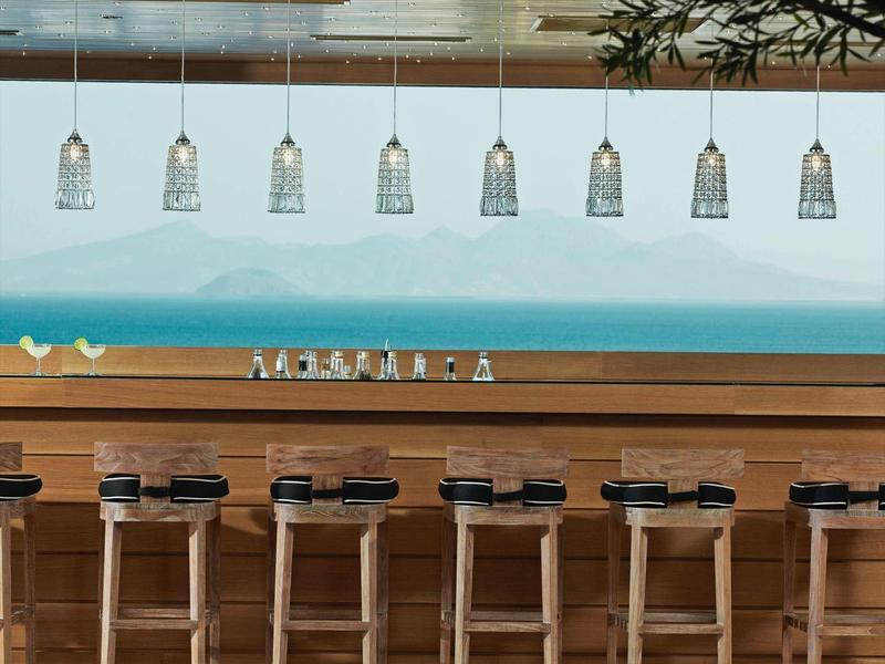 Bar moderno con sgabelli alti e lampade a sospensione, accenti eleganti in legno e blu