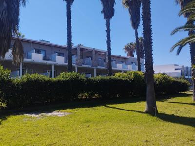 Un bâtiment d'hôtel moderne avec des balcons, entouré de palmiers et d'une pelouse verte.