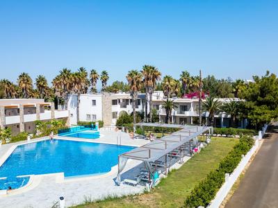 Complexe hôtelier moderne avec grande piscine, transats et palmiers sous un ciel bleu clair.