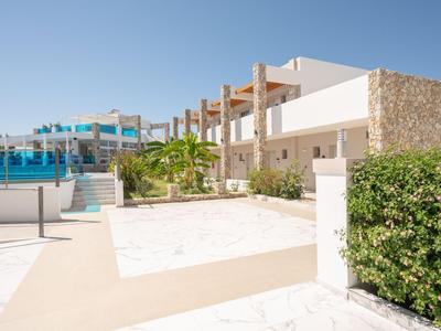 Bâtiment d'hôtel moderne avec piscine et espace extérieur ensoleillé sous un ciel clair.