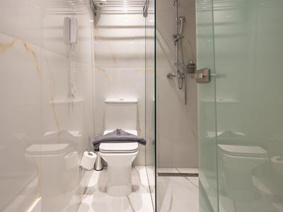 Kompaktowa łazienka z toaletą, kabiną prysznicową i nowoczesnymi białymi kafelkami.