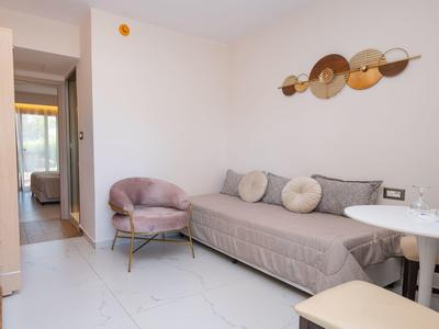 Nowoczesny, jasny salon z szarą sofą i fioletowym fotelem w pokoju hotelowym.