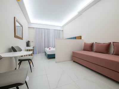 Nowoczesny pokój hotelowy z kanapą, łóżkami, krzesłami i biurkiem w jasnym stylu.