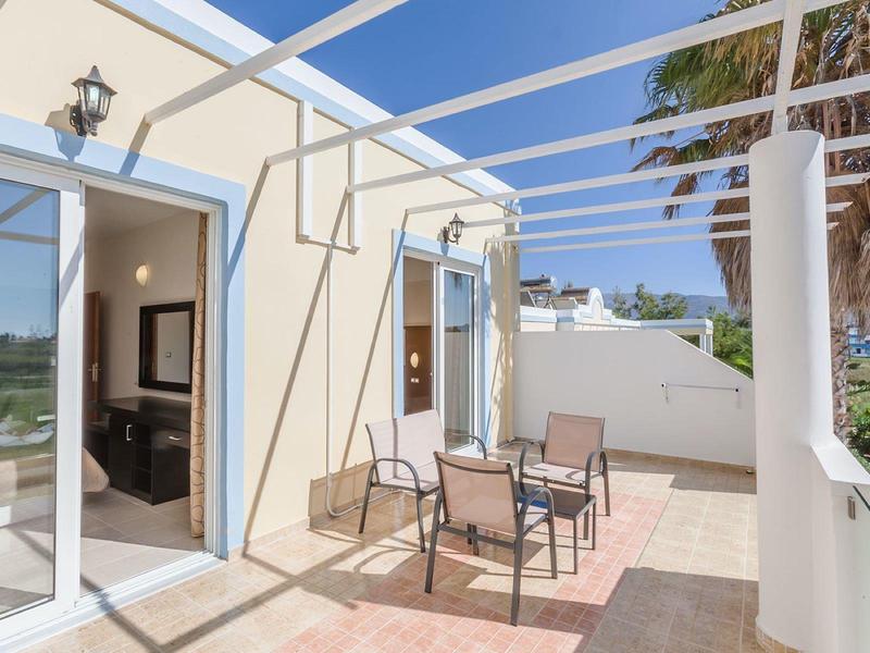 Taras z meblami ogrodowymi przy jasnym domu wakacyjnym w słońcu.