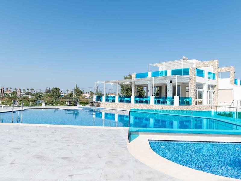 Nowoczesny kompleks hotelowy z basenem na świeżym powietrzu i czystym niebieskim niebem podczas słonecznej pogody.