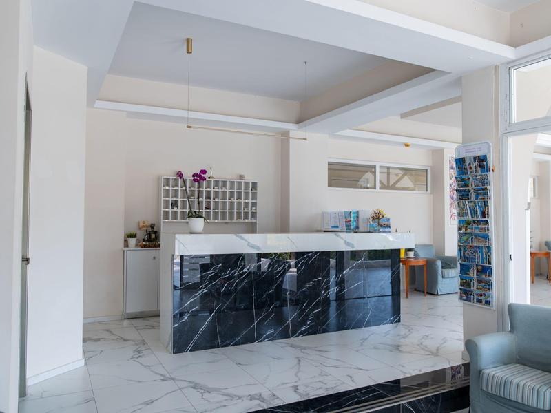 Jasna recepcja hotelowa z czarnym marmurowym kontuarem i materiałami informacyjnymi w nowoczesnym salonie.