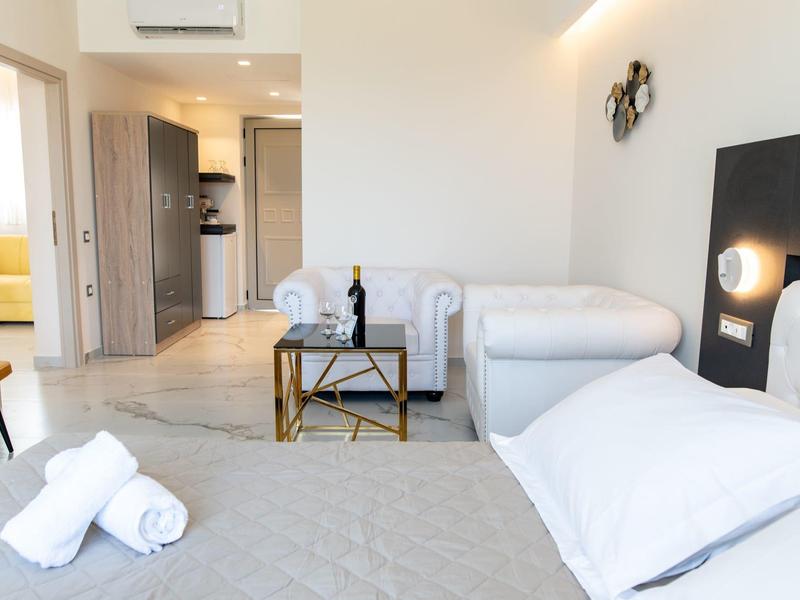 Nowocześnie urządzone pokoje hotelowe z łóżkiem, sofą i stolikiem w jasnej, przyjaznej atmosferze.