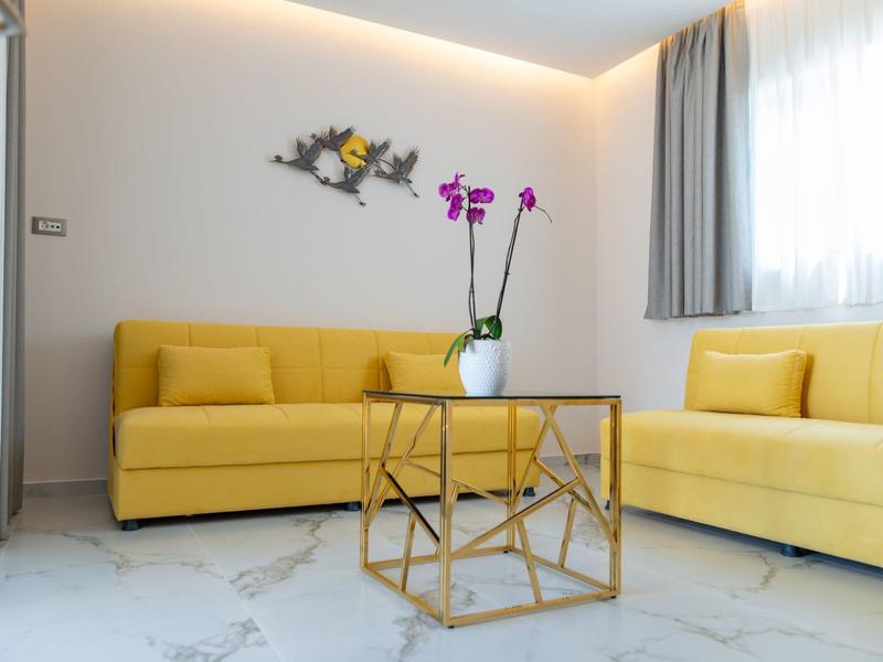 Nowoczesny salon z żółtymi sofami, złotym stolikiem i orchideą w wazonie.