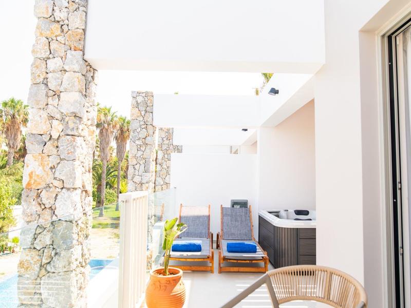 Nowoczesny teren na zewnątrz z basenem, kamiennymi filarami i dwoma fotelami na tarasie.