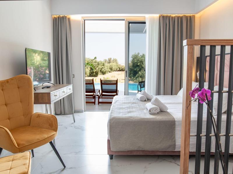 Nowoczesny pokój hotelowy z łóżkiem, fotelem, telewizorem i tarasem z widokiem na basen.