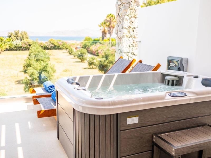 Wanna z hydromasażem na tarasie z widokiem na ogród i morze w tle.