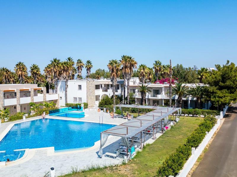 Nowoczesny basen hotelowy z białymi budynkami, leżakami i palmami pod czystym niebieskim niebem