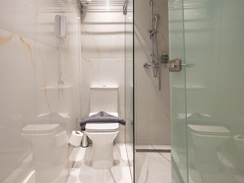 Kompaktowa łazienka z toaletą, kabiną prysznicową i nowoczesnymi białymi kafelkami.