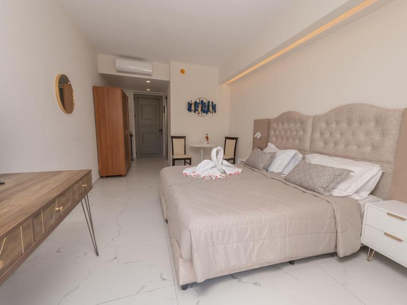 Jasny pokój hotelowy z podwójnym łóżkiem, biurkiem, klimatyzacją i nowoczesnym wystrojem.