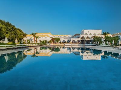 Blick auf ein großes, ruhiges Becken mit Spiegelung von Gebäuden und blauem Himmel.