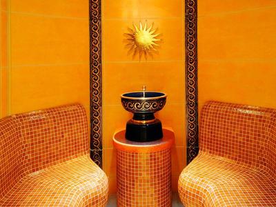 Ein Raum mit orangen Mosaik-Sitzbänken, orange Wänden und einem kleinen runden Tisch mit Schale.