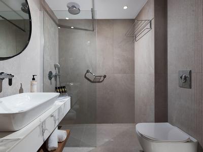 Moderne, helle Badezimmereinrichtung mit Glasdusche, großem Spiegel und weißen Sanitärobjekten.