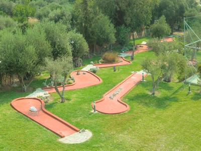 Minigolfanlage mit mehreren Bahnen, umgeben von Bäumen und Rasenflächen.