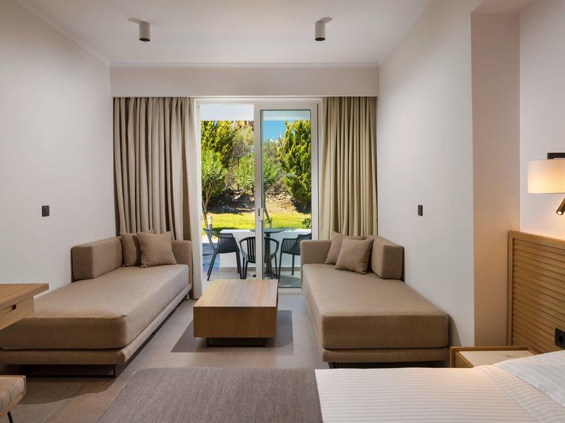 Modernes Wohnzimmer mit zwei braunen Sofas, einem Holztisch und Blick auf Terrasse und Garten.