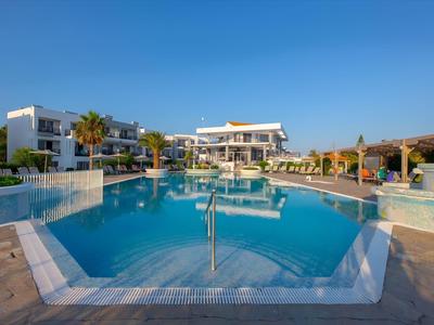 Großer Pool vor einem modernen Hotel unter klarem blauem Himmel.