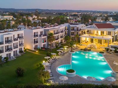 Moderner Hotelkomplex mit beleuchtetem Pool, Liegestühlen und umliegender Landschaft bei Abenddämmerung.
