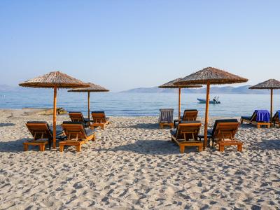 Strand mit Liegestühlen und Sonnenschirmen aus Holz am ruhigen Meer.