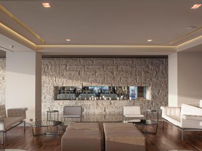 Area lounge dell'hotel moderna e luminosa con facciata in pietra e comode poltrone.