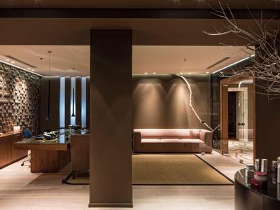 Moderní hotelový salonek s hnědými pohovkami, teplým osvětlením a dřevěnými prvky