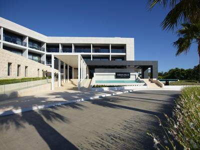 Edificio di hotel moderno con piscina e palme sotto un cielo azzurro limpido
