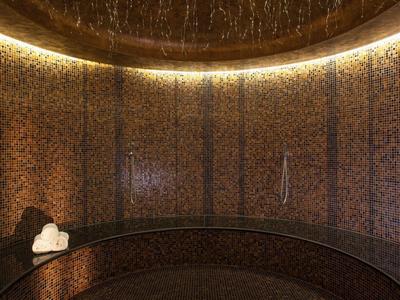 Zakřivený vnitřní posezení s propracovanými mozaikovými stěnami a teplým ambientním osvětlením.