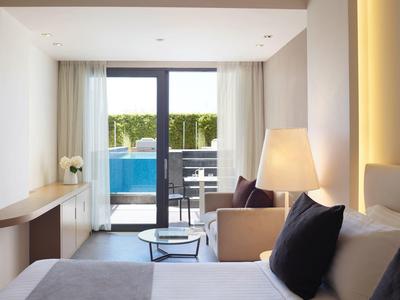 Moderní hotelový pokoj s velkým oknem s výhledem na bazén a terasu.