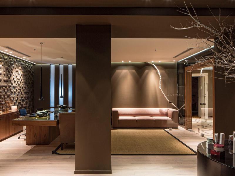 Moderní hotelový salonek s hnědými pohovkami, teplým osvětlením a dřevěnými prvky