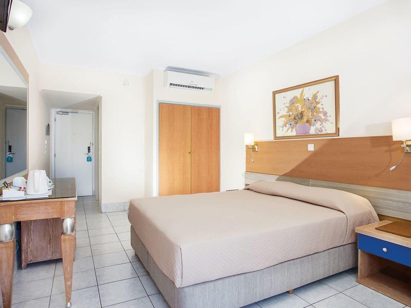 Habitación de hotel luminosa con cama doble, escritorio, armario y aire acondicionado.