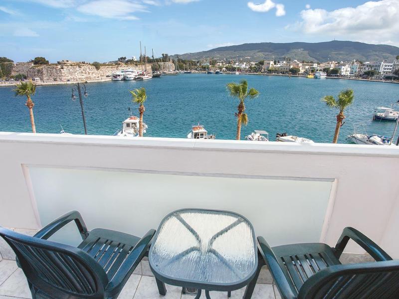 Balcón con mesa y sillas con vista al puerto y la ciudad bajo cielo despejado.