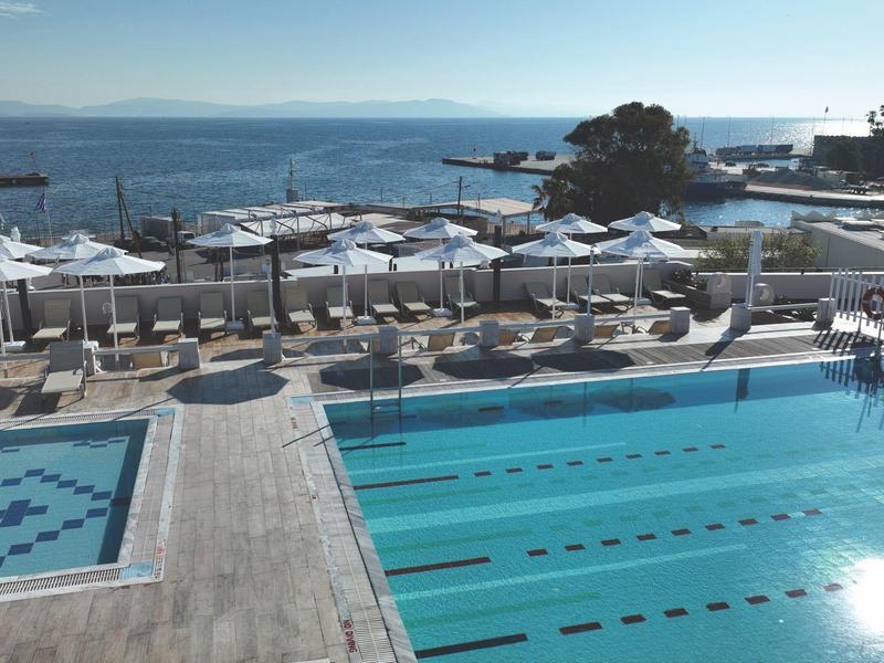 Piscina exterior moderna con tumbonas y vista al mar en un destino soleado de vacaciones.