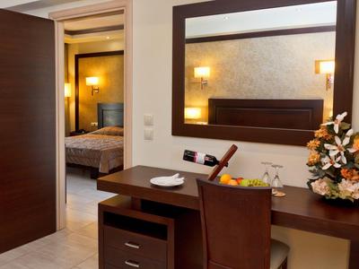 Escritorio con silla, decoración y espejo en una habitación de hotel con vista al dormitorio.