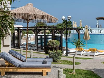 Área de piscina con tumbonas, sombrillas y vista al mar bajo un cielo despejado.