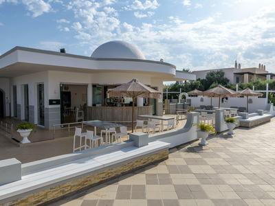 Modernes Gebäude mit Sitzbereich und Sonnenschirmen an einem hellen, sonnigen Tag.