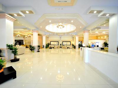 Großer, heller Hotellobby-Bereich mit weißen Böden und eleganter Beleuchtung.