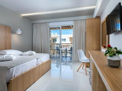 Modernes Hotelzimmer mit Doppelbett, Balkon und Holzmöbeln in hellem Design.