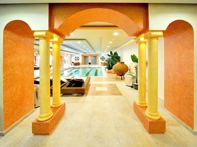 Pasillo de hotel bien iluminado con columnas de colores cálidos y vista a la zona de la piscina.