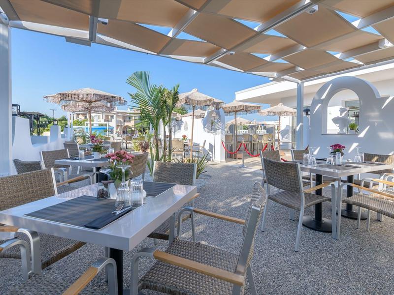 Terraza con mesas y sillas al aire libre de un hotel durante el día.