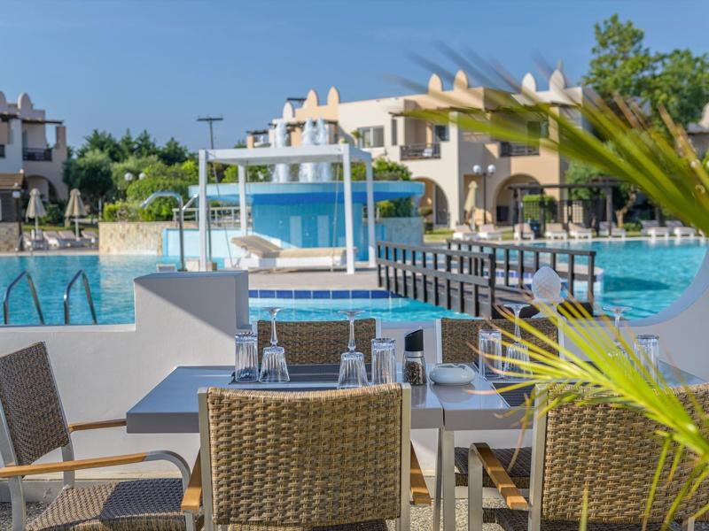 Área moderna de piscina al aire libre con terraza soleada y asientos en un complejo vacacional.